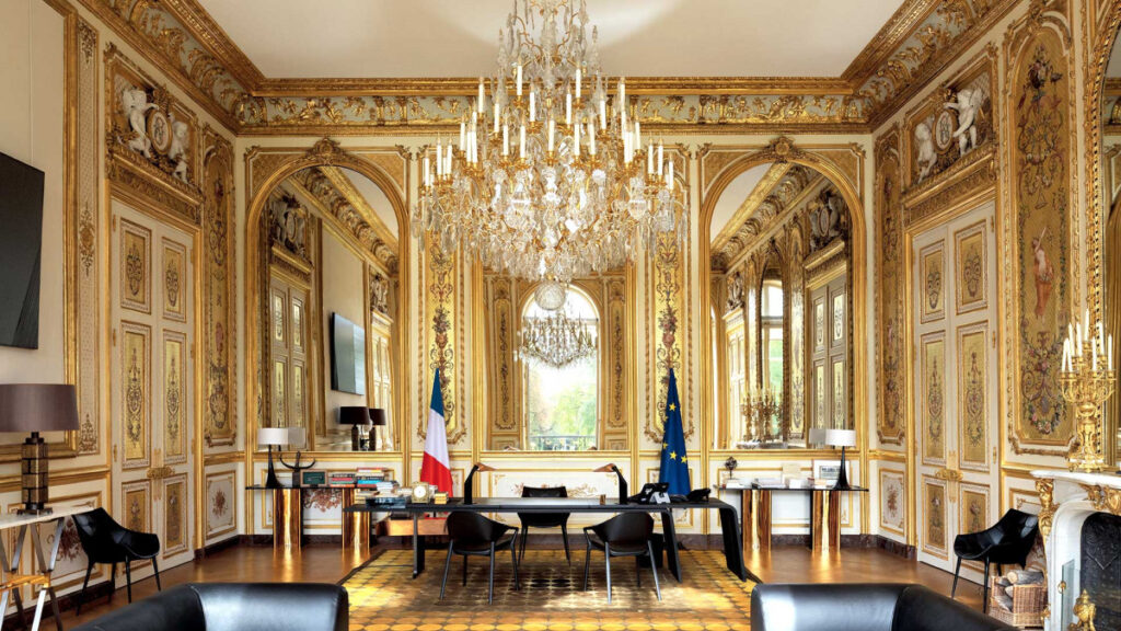 Salle dorée avec mobilier moderne et drapeaux français.